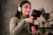 © Studio Marmellata - A young woman wearing headphones holds a camera with a monitor attached, focusing on her work.
