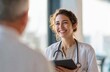 © Andy - Female doctor with curly hair wearing white lab coat and stethoscope smiling while consulting with a patient in a modern clinical setting