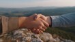 © Bussakon - Two hands shaking in a handshake amidst a scenic mountain vista symbolizing a successful agreement and partnership
