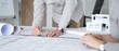 © rogerphoto - Architects are discussing building plans, using a compass over blueprints while collaborating on a new construction project in an office, emphasizing design, planning, and teamwork, close up