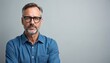 © Vadym - Mature caucasian man with glasses wearing blue shirt. He looks seriously at camera with a neutral expression. Simple studio portrait with gray background. Experienced adult male pose.