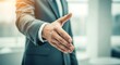 © MopoWe - Businessman reaching out hand for a handshake in a bright modern corporate office during golden hour sunset with warm lens flare and bokeh light