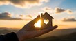 © Wool World - Hand holding a miniature wooden house with a heart cutout, illuminated by a warm sunset, symbolizing the dream of home, love, and future security
