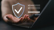 © Nirusmee - Close-up of person using laptop with holographic shield icon, representing cybersecurity, data protection, privacy, encryption, and secure authentication access in digital environment.