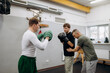 © m-art - Two men are training in a cozy gym, focusing on boxing skills. One person wears green gloves while the other teaches techniques in a supportive environment.