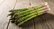© Dara - A bunch of fresh green asparagus spears tied with twine on a rustic wooden table.