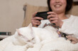 © hakase420 - ゲームをする飼い主の膝の上で毛繕いをする猫