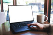 © Farknot Architect - Mockup image of a woman working on laptop computer with blank white desktop screen while drinking coffee in cafe