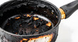 © Suwantono - Close-up of a severely burnt saucepan with scorched food residue, illustrating a common cooking mishap and the challenge of cleaning a ruined pot after a kitchen accident