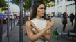© Krakenimages.com - Young hispanic woman with arms crossed x on busy downtown urban street full of pedestrians; defiance.