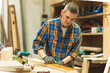 © ALIDA - Woodworker applying wood wax finish in workshop