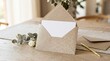 © Natalia - Gold Glitter Envelope with White Card on Wooden Table for Wedding Invitation