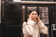 © zvkate - Annoyed young woman rolling eyes and holding hands to head on city street, frustrated female traveler in beige trench coat showing irritation, negative emotion and stress concept