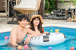 © buritora - A young Asian couple playing with inflatable rings in a swimming pool (vacation, resort, vacation, overseas travel)