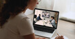 © fizkes - Different business professionals gathered in modern boardroom, negotiates, take part in videoconference talk with partners, laptop screen view female shoulder sit at desk review data, writing notes