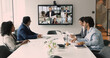© fizkes - Diverse international business team discussing teamwork, work strategy, planning deal, partnership on online hybrid video conference, meeting at table and large screen, talking