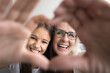 © fizkes - Close up happy faces view though joined fingers showing love symbol, granny and little granddaughter smile, revealing white teeth, advertising dental clinic service, medical insurance cover for family