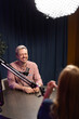 © fizkes - Announcer recording audio podcast during live broadcasting in studio. Host speaks into microphone, engaging in conversation with guest, producing digital content for online blog or streaming channel
