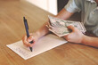 © Anna Zhukkova - Child counting dollar bills over finance notes on wooden desk, young kid learning to manage money and savings, financial literacy education concept indoors, close up Hands with money