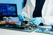 © Nuttapong punna - Technician inspecting computer motherboard with magnifying glass in a high-tech electronics lab, focusing on hardware diagnostics, cybersecurity system