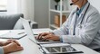 © Liew - Doctor utilizing laptop and tablet for online medical consultation and patient care in modern healthcare setting