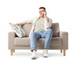 © Pixel-Shot - Young man talking by mobile phone on grey sofa against white background