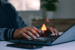 © MUNTHITA - Concept of cyber security breach, computer virus, data system failure and software bug error. Professional programmer or hacker hand typing on laptop with warning alert icons and coding overlay.
