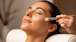 © Buka - Woman enjoying facial treatment at spa, receiving skincare application with brush, relaxation and beauty.