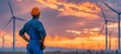 © haidar - maintenance engineer observes wind turbines at sunset