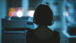 © Moddy - A woman sits in an office at night, illuminated by the soft glow of distant bokeh lights. The atmosphere is quiet and contemplative