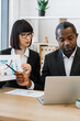 © sofiko14 - A woman points at a financial chart while discussing with an African American man during a business meeting