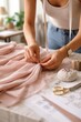 © Marina Dubin - Hands sewing neutral fabric over pattern papers, ideal for fashion development, garment making, tailoring service and textile craftsmanship