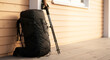 © Iryna - Black trekking backpack with hiking poles on wooden porch, outdoor adventure gear and travel preparation