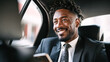 © Kowit - A well-dressed man smiles while sitting in the back seat of a car, holding a smartphone.