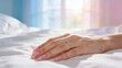 © Stocky Boi - Gentle woman's hand with ring resting on clean white bed sheets in soft morning light.