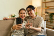 © MIND AND I - Couple Taking a Selfie with Smartphone on Sofa at Home