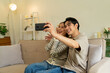 © MIND AND I - Couple Taking a Selfie with Smartphone on Sofa at Home