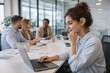 © Pavel - young businesswoman wearing a hearing aid focuses on her laptop in a meeting room, representing workplace inclusion, accessible technology, concentration and modern office teamwork