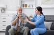 © New Africa - Care worker supporting senior man with walking cane indoors