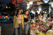 © Apichat - Young women shopping at vibrant asian night market