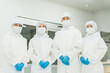 © buritora - Male and female staff working in a manufacturing plant, wearing protective suits and cleanroom wear.