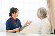 © buritora - A female caregiver (home care) conducts a medical interview with a senior woman in a wheelchair.