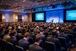 © Meow Creations - Large audience of business professionals at a corporate conference listening to a speaker on stage