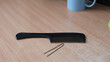 © Michel F - Black plastic comb and hairpin lying on light wooden table .