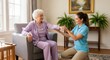 © Chenda - An elderly woman sits in an armchair, holding her hand out to a young caregiver who is kneeling beside her, gently taking her hand. They are in a warmly lit living room with a window