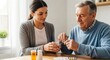 © Chenda - A young woman is assisting an elderly man in taking his medication. She holds a glass of water while he carefully takes pills from a small plastic container.