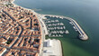 © VectorGenius - Aerial view of a coastal city with a marina and boats docked in the harbor near buildings