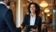 © miss irine - Smiling hotel staff member shakes guest hand holding tablet. Professional hospitality and luxury service in a modern lobby. Warm indoor light, positive welcome.