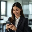 © Kasiraporn Meearsa - Confident Asian businesswoman using smartphone in modern office, smiling professional lifestyle