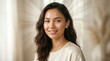 © SnapNshine - Woman with long dark hair smiles warmly in a bright, airy room, creating an inviting atmosphere that suggests comfort, mindfulness, and a peaceful state of mind for editorial use.